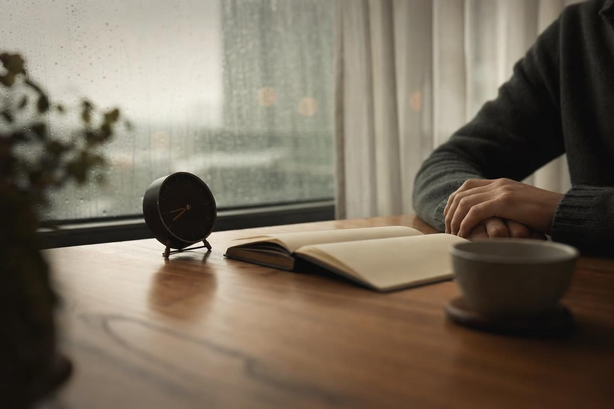 Still hands beside a desk clock and notebook, a patient calendar spread calculator planning moment as time passes